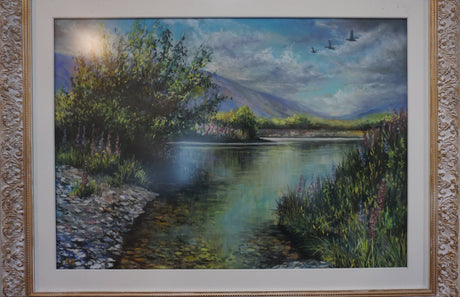 A framed landscape pastel by local artist Kathy Kerr depicting a riverscene at the Ahuriri river with the Ben O Mar mountains in the background, trees, and a cloudy sky.  Professionally framed in an ornate gold-white tone. 

